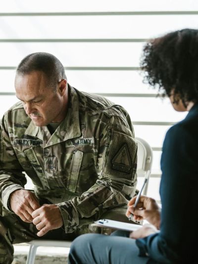A soldier in uniform discussing with a counselor in an indoor setting.