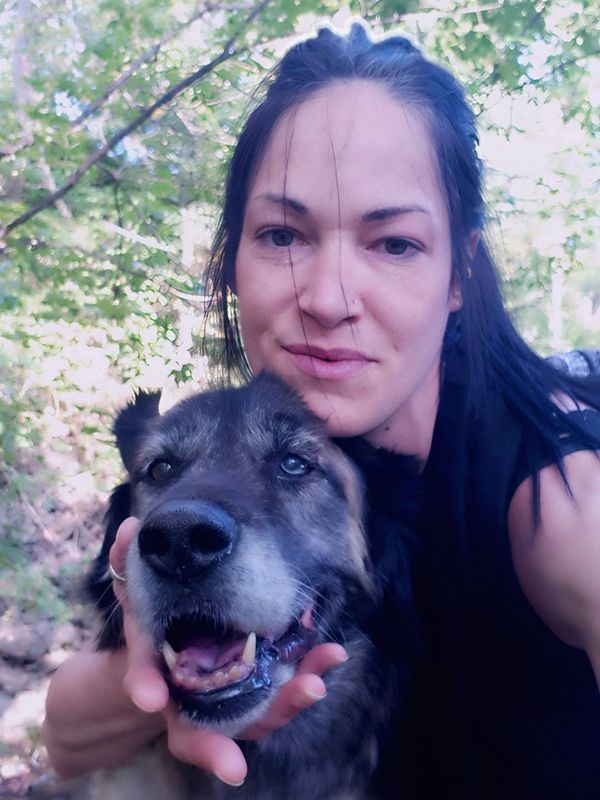 Femme posant avec un chien dans la nature.