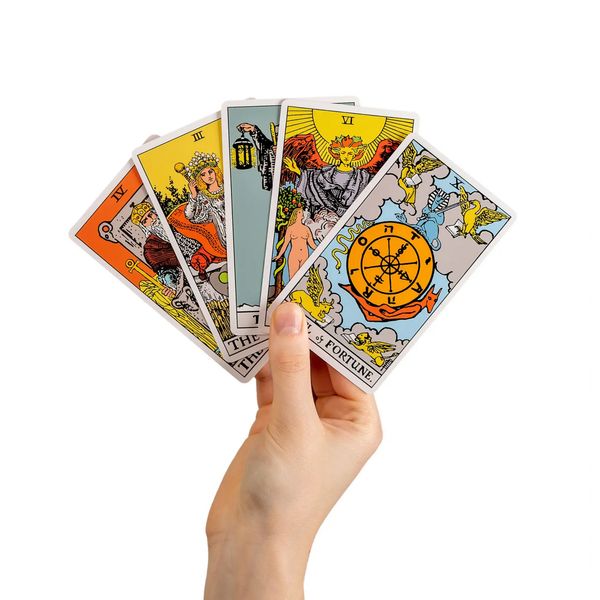 A hand holding out five tarot cards.