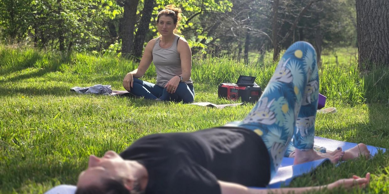 Two women doing yoga outdoors on a sunny day.