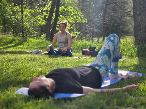 Two women doing yoga outdoors on a sunny day.