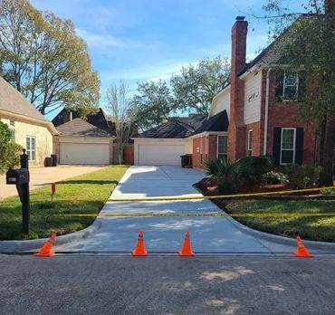 A newly poured residential driveway, beautifully finished and taped off, awaits concrete curing.