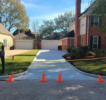 A newly poured residential driveway, beautifully finished and taped off, awaits concrete curing.