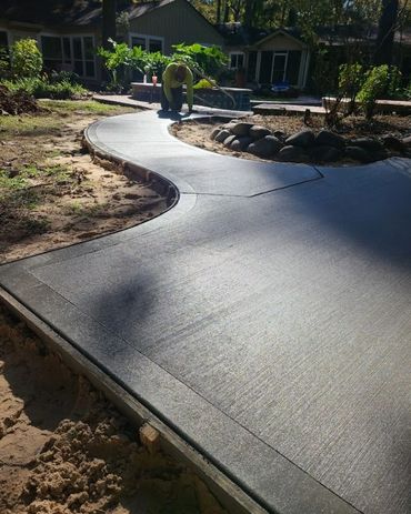 concrete patio with a curved pathway leading to the swimming pool and landscaping