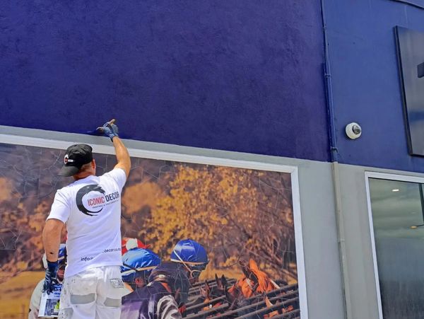 Dark blue paint applied over an exterior wall mortared with a textured render plaster finish.