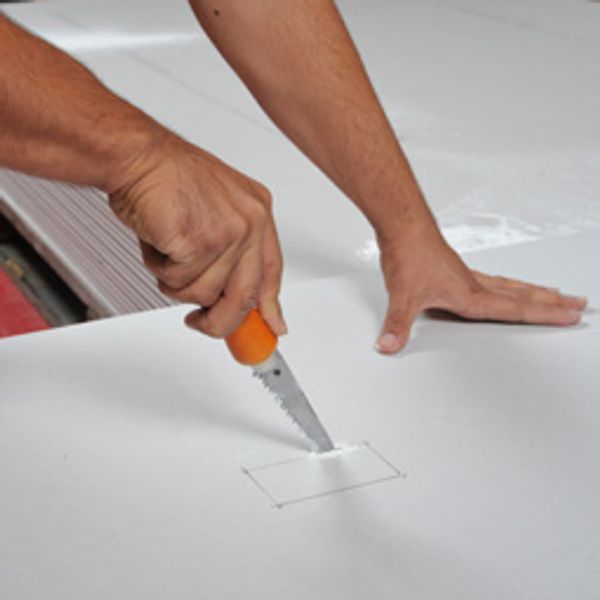 Man cutting a shape out of a board of Gib.