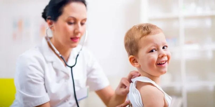 A doctor examines a smiling child.