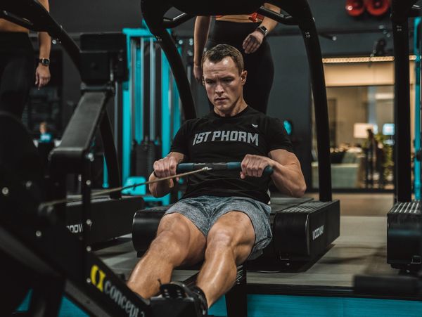 Man intensely rowing on an indoor rowing machine at the gym.