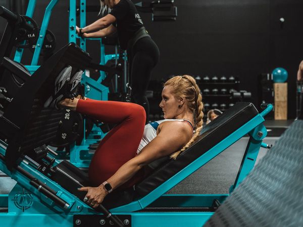 Woman working out on a leg press machine at the gym.