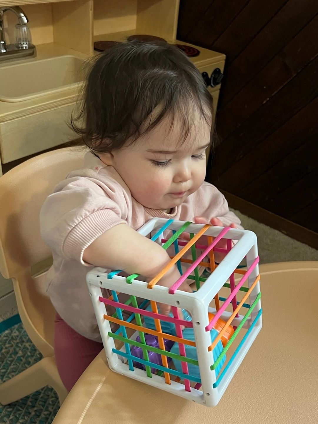 Baby playing with colorful cube toy.