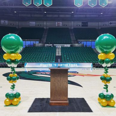 UAB Themed balloon columns flanking podium in arena for graduation event in Birmingham AL.