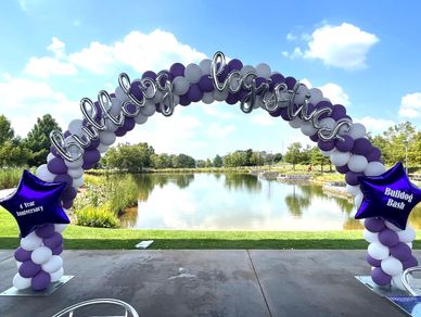 25' Sprial Balloon Arch with custom lettering in front of lake for outdoor corporate event.