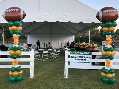 Tall outdoor balloon columns with football toppers at UAB tailgating event on Birmingham AL campus.