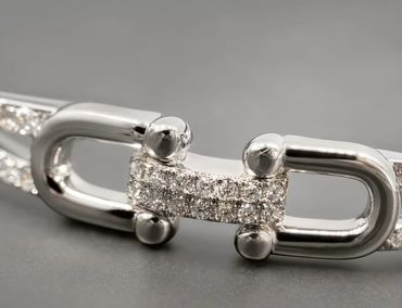 Close-up of a silver chain link with encrusted diamonds.