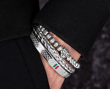 Three silver bracelets on a wrist with black clothing.