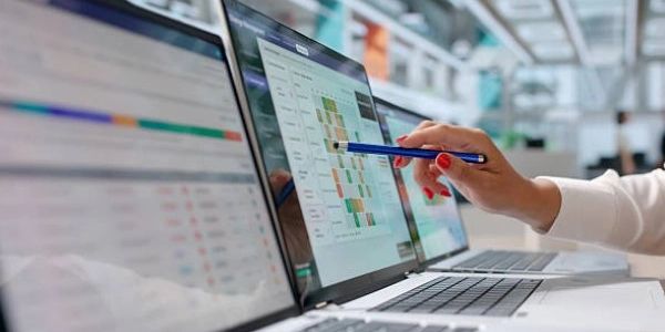 Person pointing at a laptop screen with a pen.