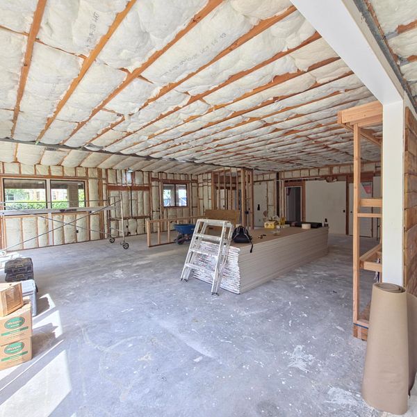 A spacious room under construction with insulation and building materials.