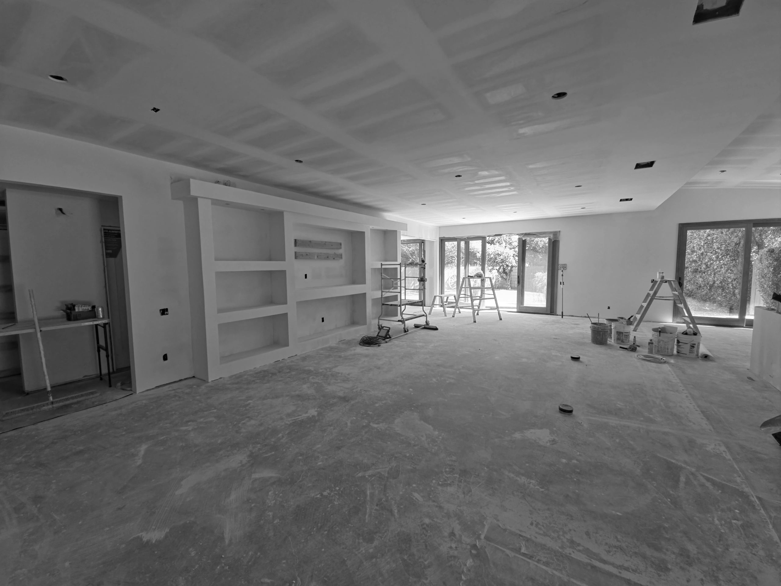 Room under construction with drywall and ladders.