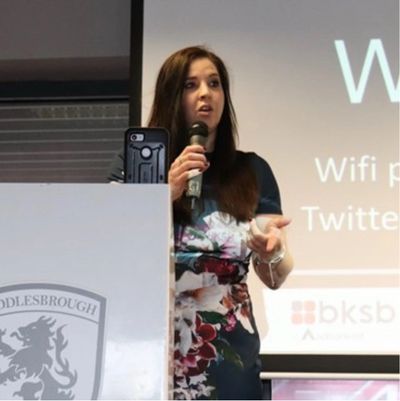 Woman speaking at a podium during a presentation.