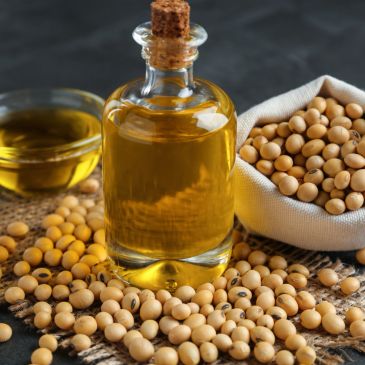 Botella de aceite con soja y semillas de soja alrededor.