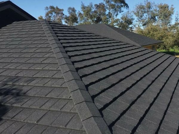 Close-up roof with gray textured steel panels that look like shingles.
