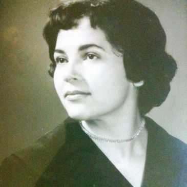 Black and white portrait of a woman with short curly hair and a pearl necklace.