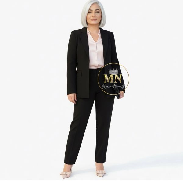 Woman in a black suit and light blouse posing confidently against a white background.