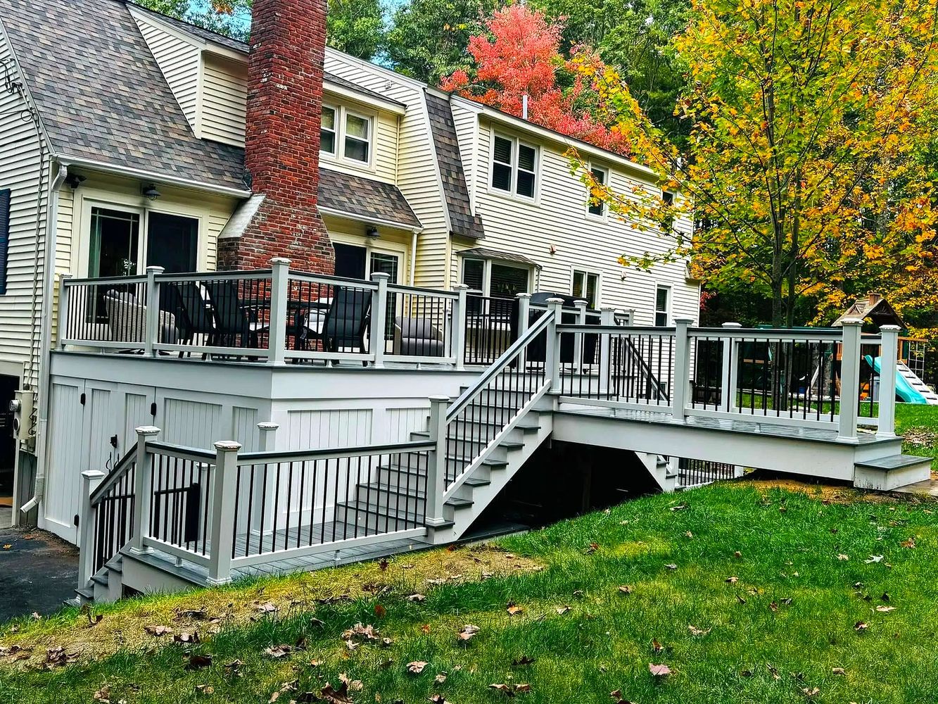 A spacious wooden deck with black railings and outdoor furniture attached to a house.