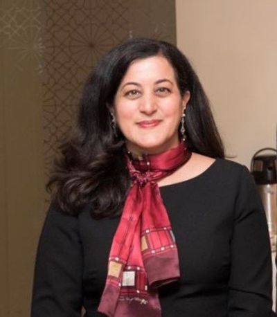 Woman with dark hair wearing a black top and red scarf.