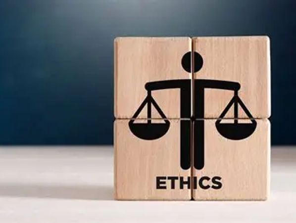 Wooden blocks forming a figure holding balanced scales labeled 'ETHICS'.