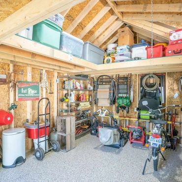 Organized shed with tools, lawn equipment, and storage bins.
