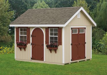 A beige garden shed with red doors and flower boxes on a green lawn.