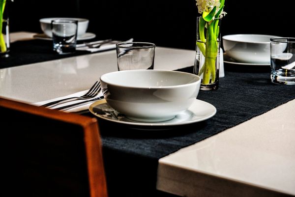 Elegant dining table set with white bowls, glasses, and a flower vase.