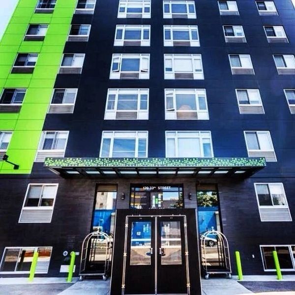 Modern black and green apartment building with multiple windows and entrance doors.
