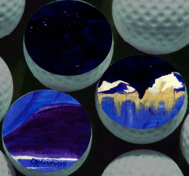 Golf balls with artistic mountain and night sky paintings inside.