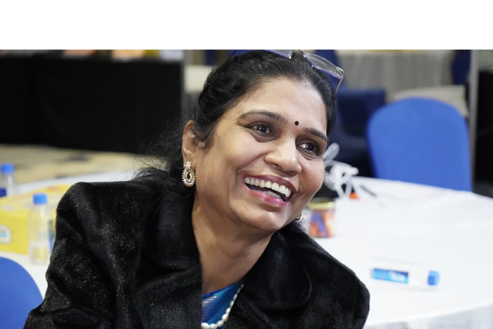 Smiling woman wearing earrings and a black coat.