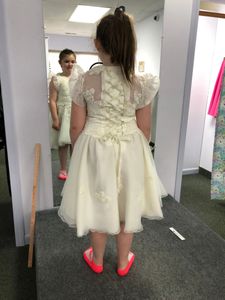 A young girl trying out a white dress