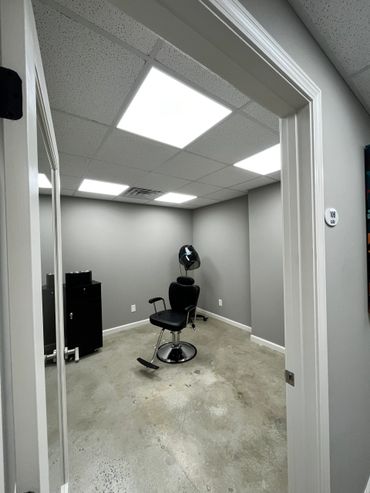 A minimalistic hair salon room with a single black styling chair and a hair dryer.