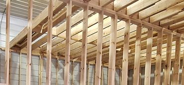 Interior view of a wooden-framed construction site with tools and a worker.
