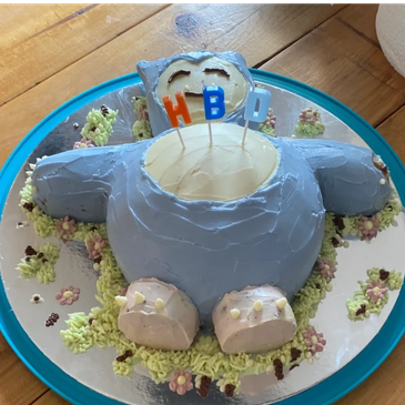 A Snorlax-shaped birthday cake with HBD candles on top.
