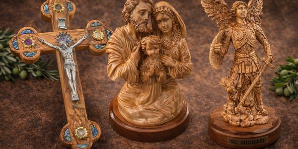 Wooden religious statues and a decorated crucifix on a brown surface.