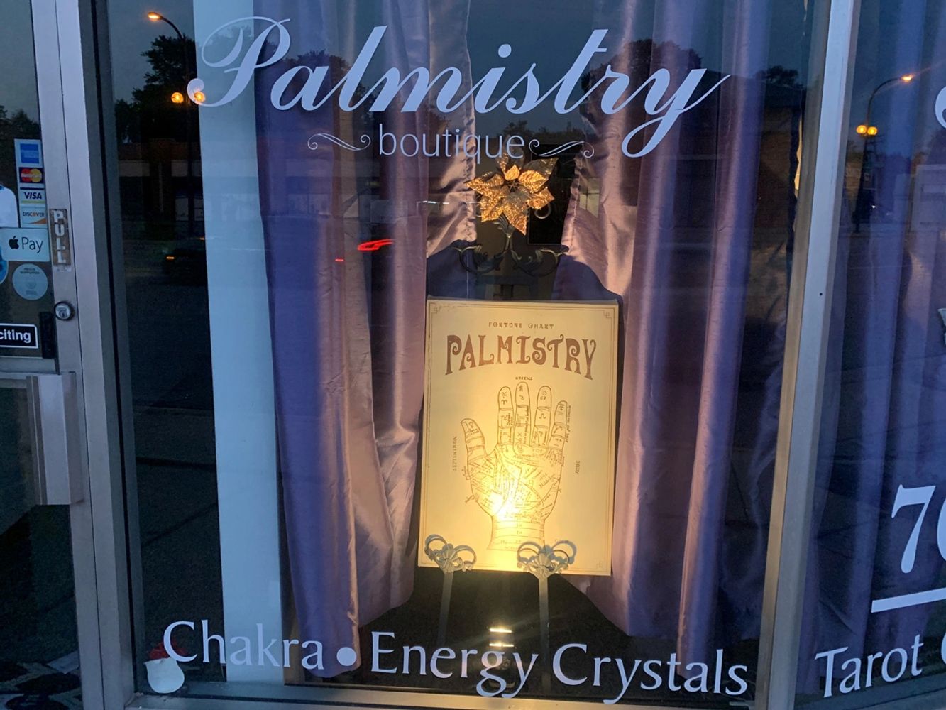 Palmistry Boutique's front window featuring a Palmistry sign, Chakra, Energy Crystals, and Tarot.