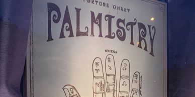 Front window of Palmistry Boutique featuring a Palmistry sign with details on the palm of a hand.