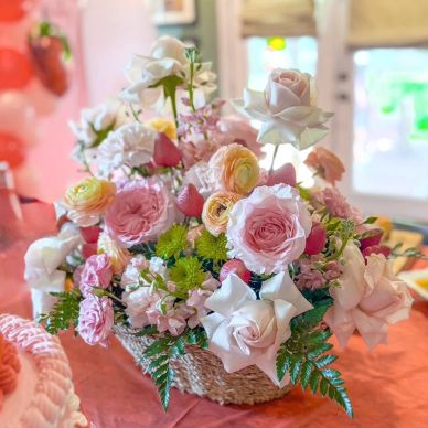 A colorful basket of assorted flowers on a table.