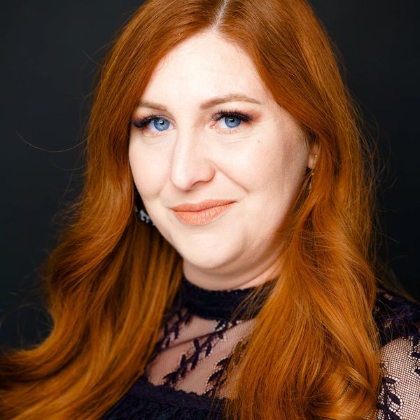 Portrait of a woman with long red hair and blue eyes.