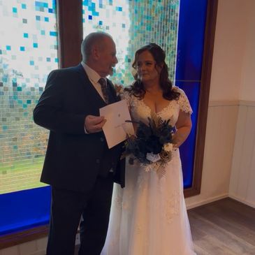 Bride and groom posing inside by stained glass window.