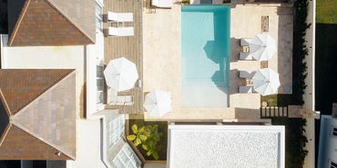 Aerial view of a modern home with a pool and white umbrellas.