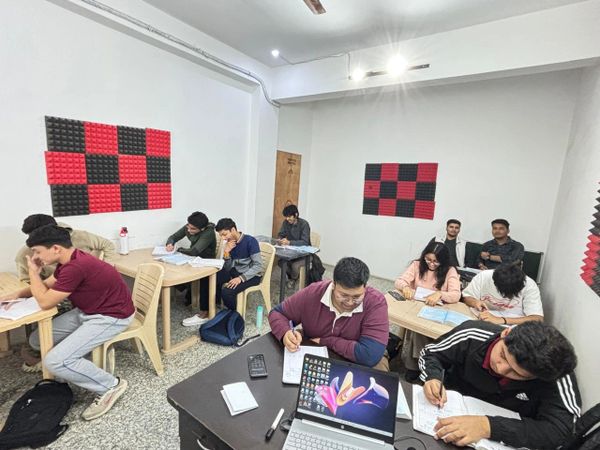 Students studying and writing in a well-lit classroom with acoustic panels.