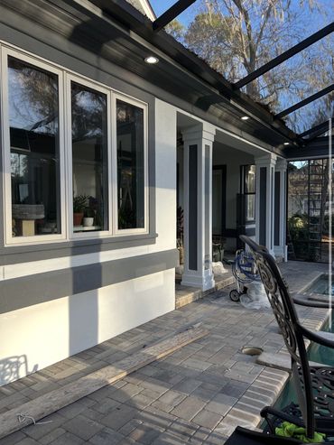Smooth white stucco wall with gray trim and painted columns on a covered patio