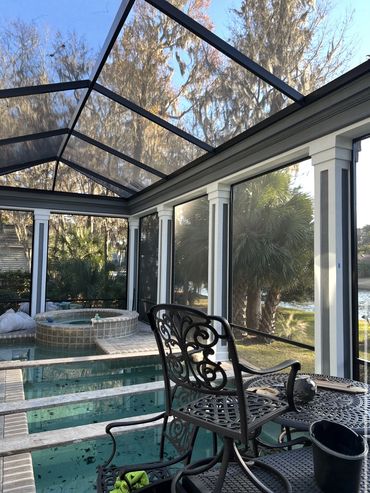 Freshly painted screened pool enclosure with white columns and dark trim